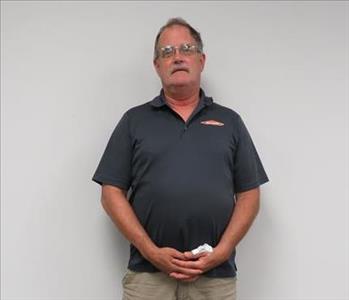 Male employee Bill Garner standing in front of a muted wall.