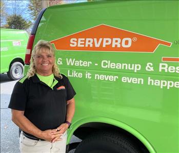 Female employee Pam Butts standing in front of a SERVPRO vehicle.